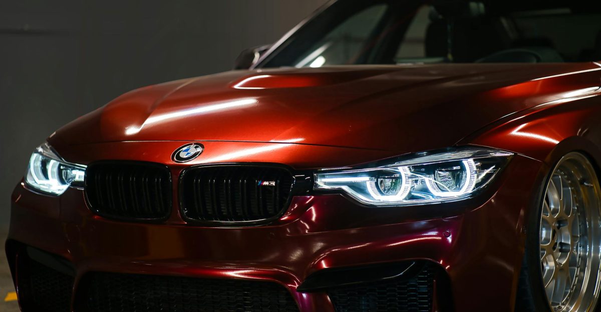 Close-up of a luxury red BMW with a sleek shiny hood captured indoors