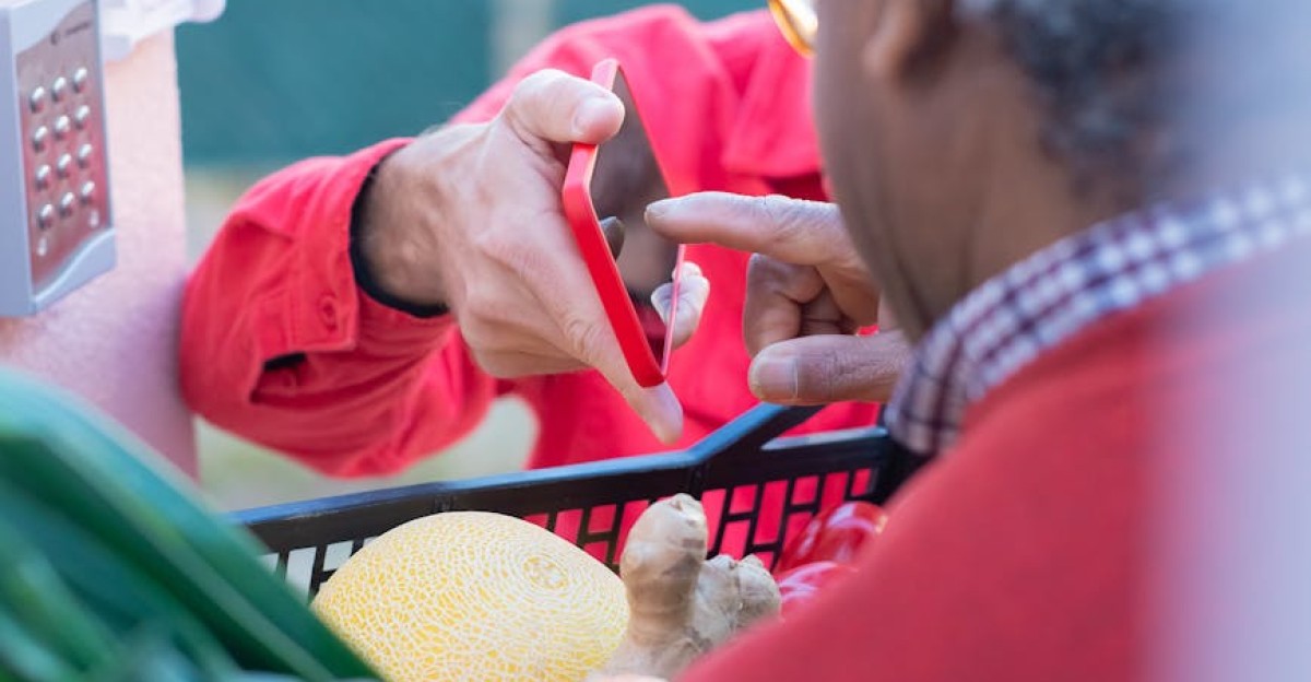 Senior man using smartphone during grocery shopping outside carrying vegetables in Portugal