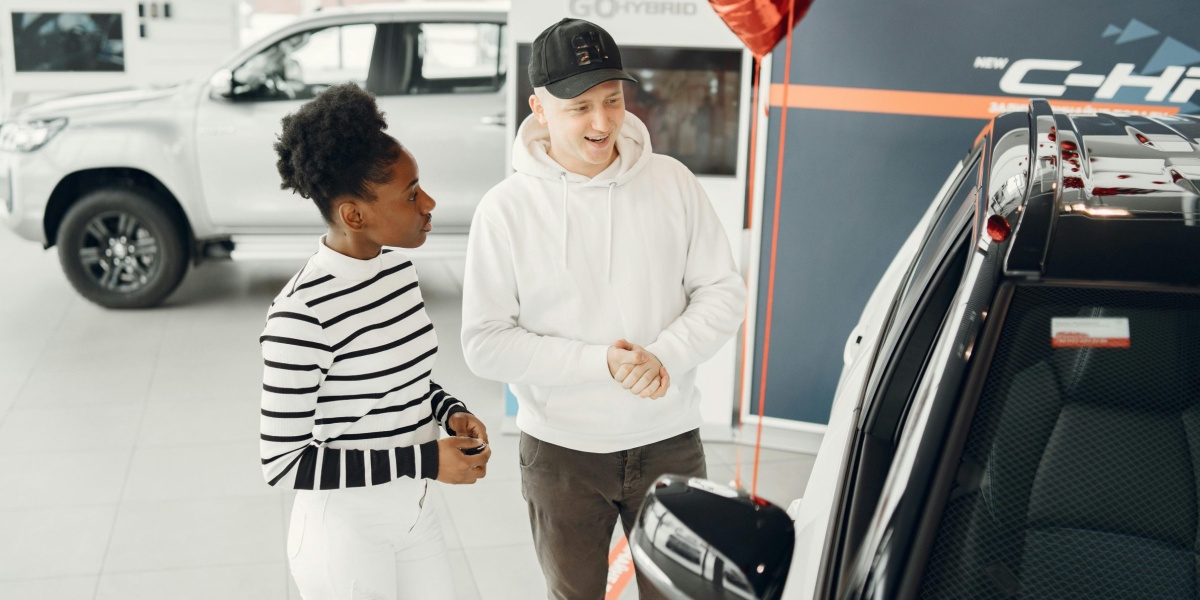A young couple examines cars in a modern dealership showroom, highlighting customer experience.