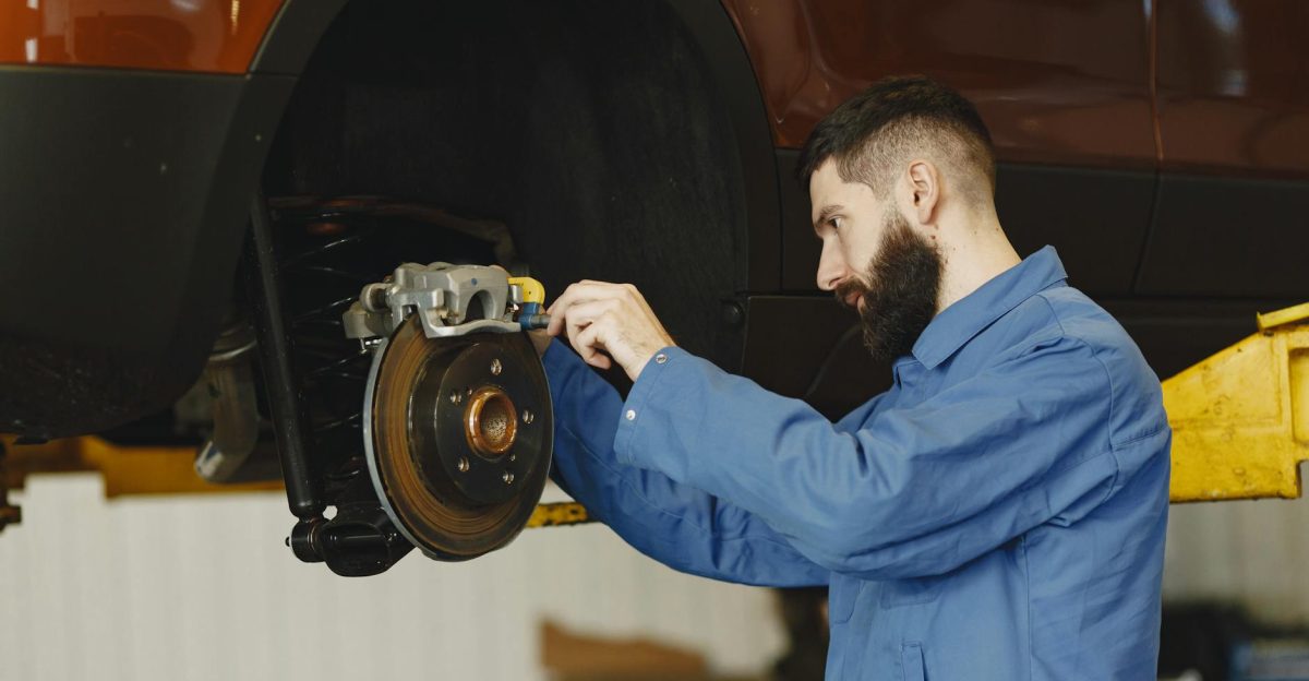 Mechanic in blue uniform performing brake repair on car in modern garage
