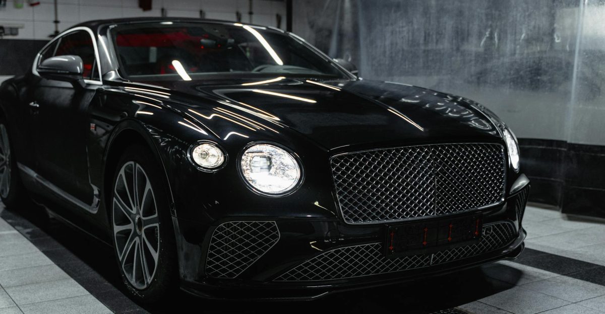 Sleek black luxury car in a modern indoor car wash setting showcasing elegance and sophistication
