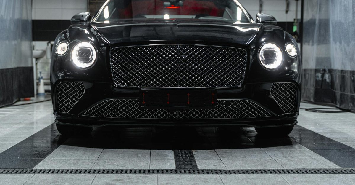 Front view of a sleek black Bentley inside a car wash showcasing elegance and luxury