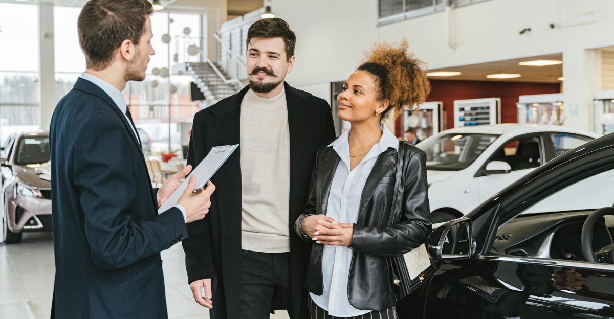 Couple discussing car purchase with salesman at indoor dealership engaging conversation