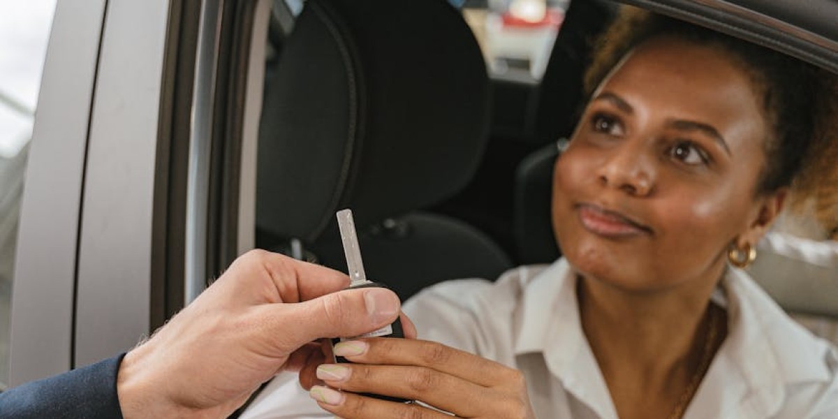 A woman in a car receives keys from a salesperson symbolizing a new vehicle purchase