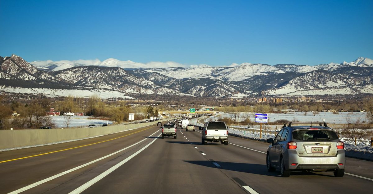 A scenic highway view surrounded by snow-capped mountains under a clear blue sky showcasing traffic flow in Colorado