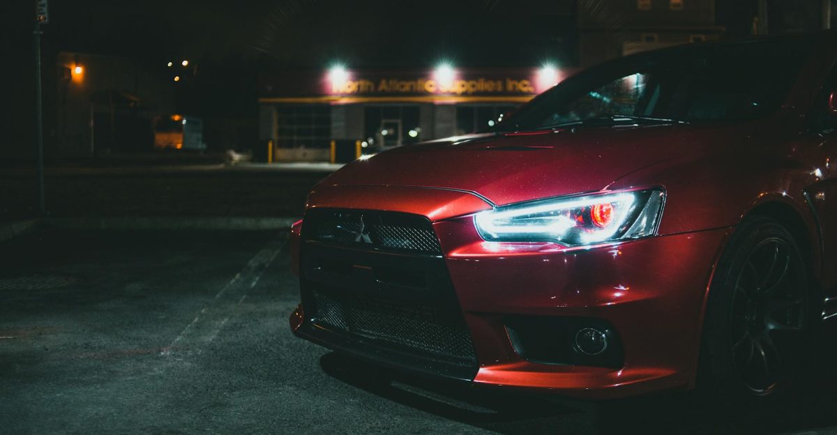 Close-up of a red Mitsubishi car s headlight shining brightly at night showcasing modern design and detail
