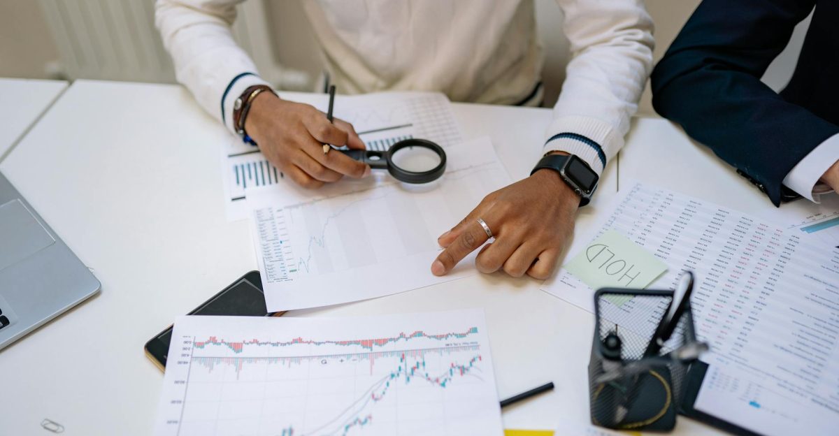 Business professionals reviewing charts with a magnifying glass in an office setting