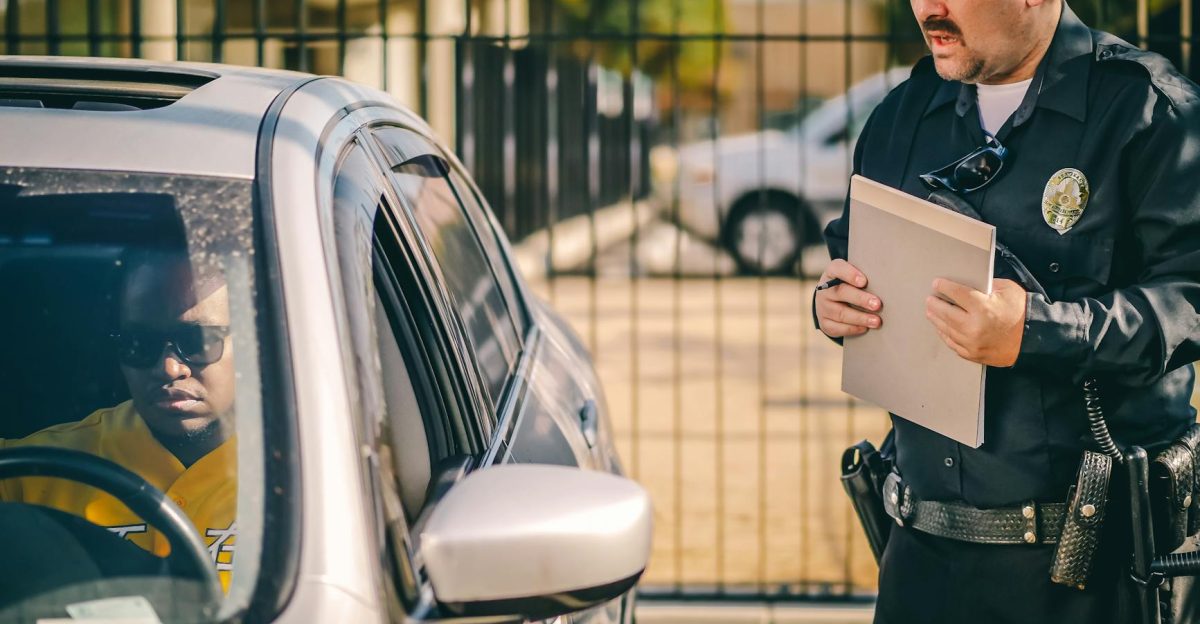 Police officer at car window issuing a ticket to a driver in a sunny outdoor setting