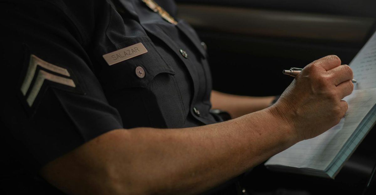 Close-up of a police officer writing in a notebook while sitting in a car focused detail