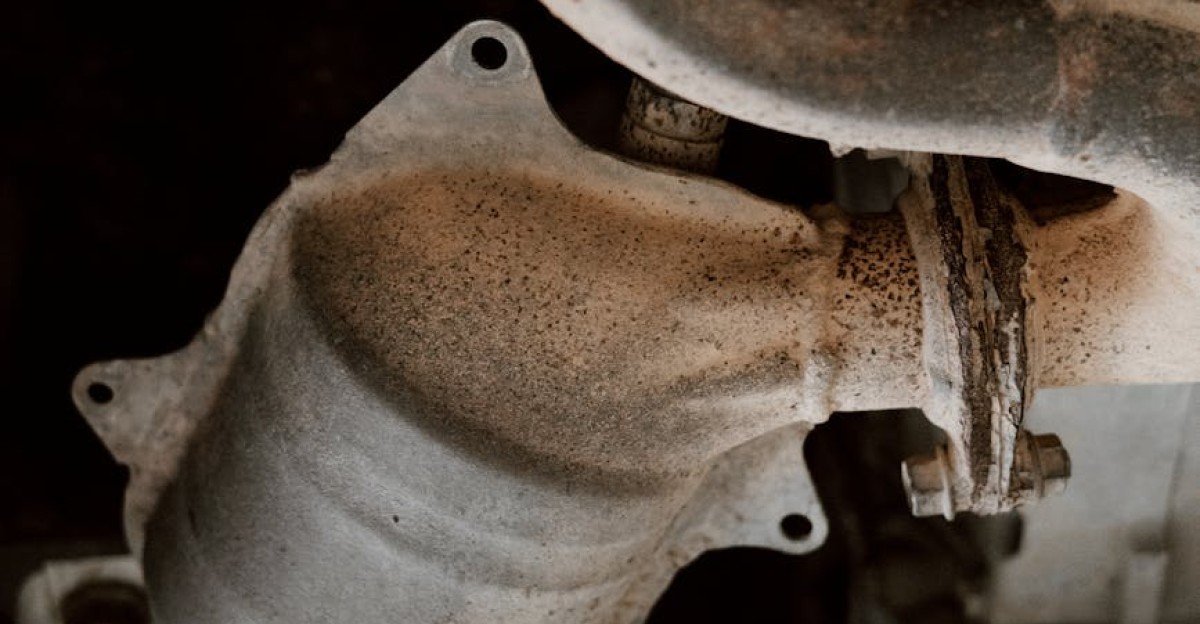 Detailed close-up of rusted exhaust system parts under a vehicle
