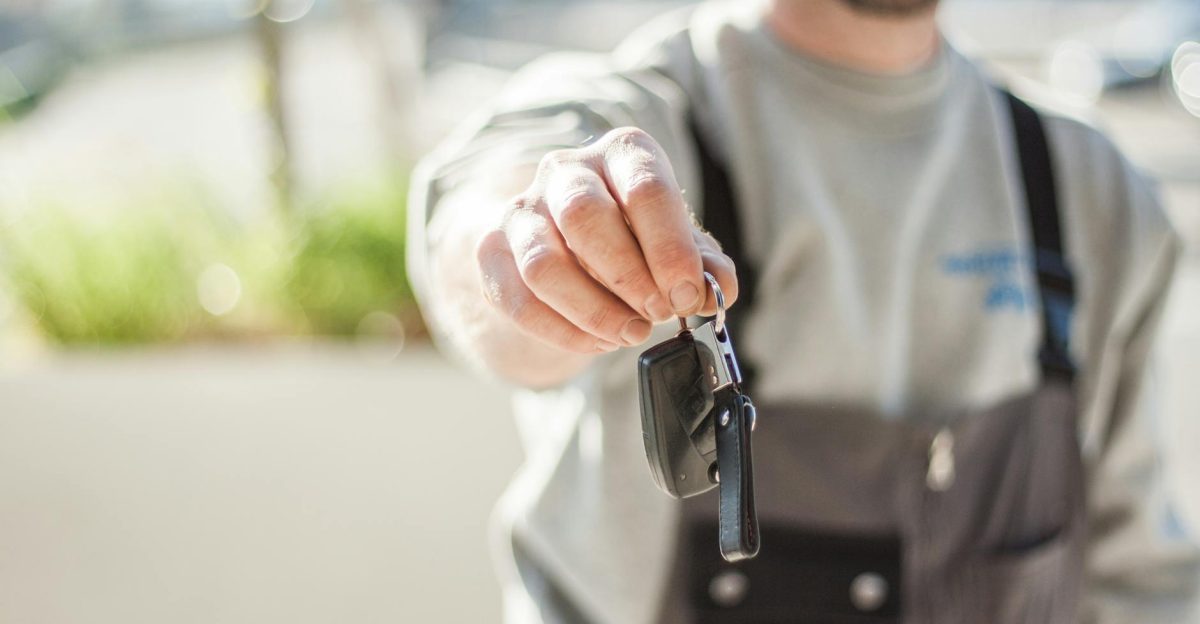 Hand holding a car key outdoors blurred background shallow focus