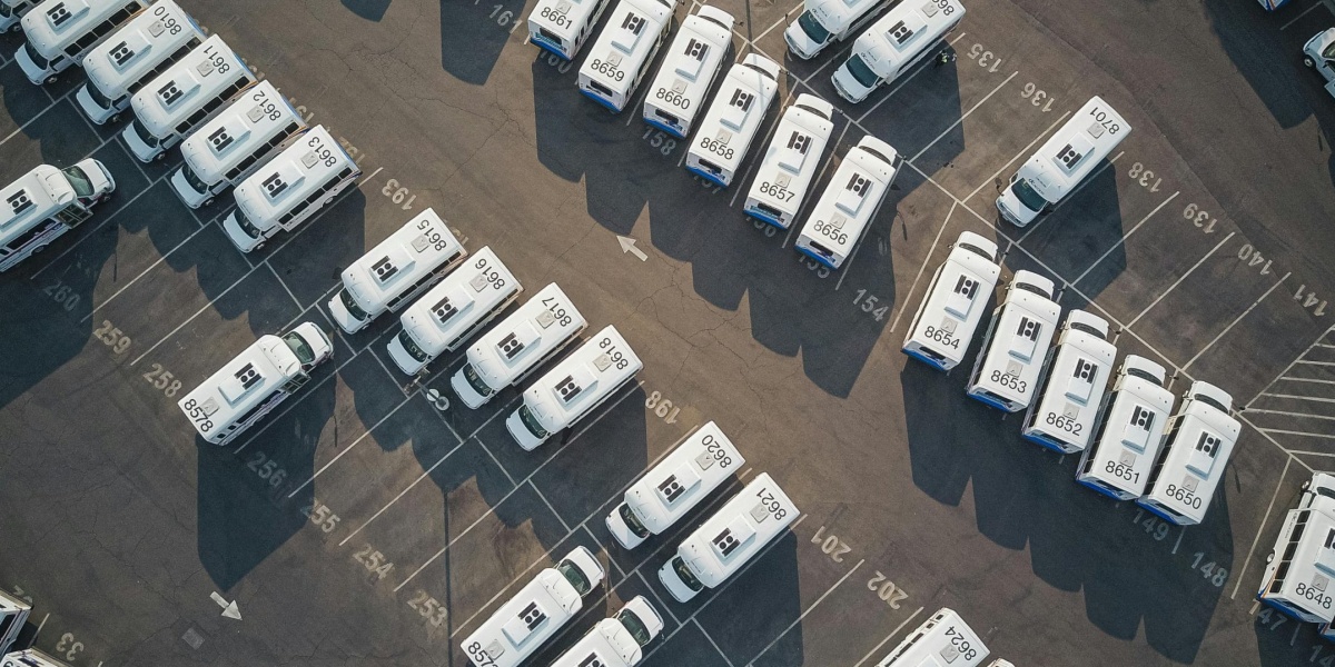 Aerial drone shot of neatly organized vans in a large parking lot.