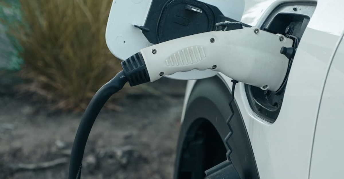 Close-up of electric vehicle connected to charging station outdoors