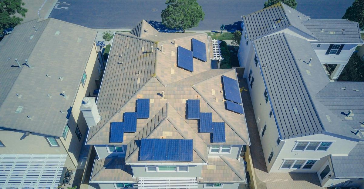 Aerial view of suburban homes equipped with solar panels in a sunny neighborhood