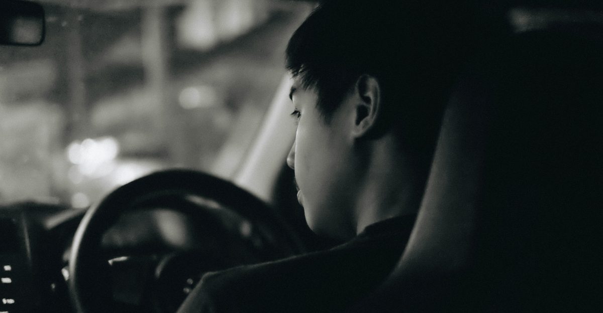 grayscale photography of man driving car