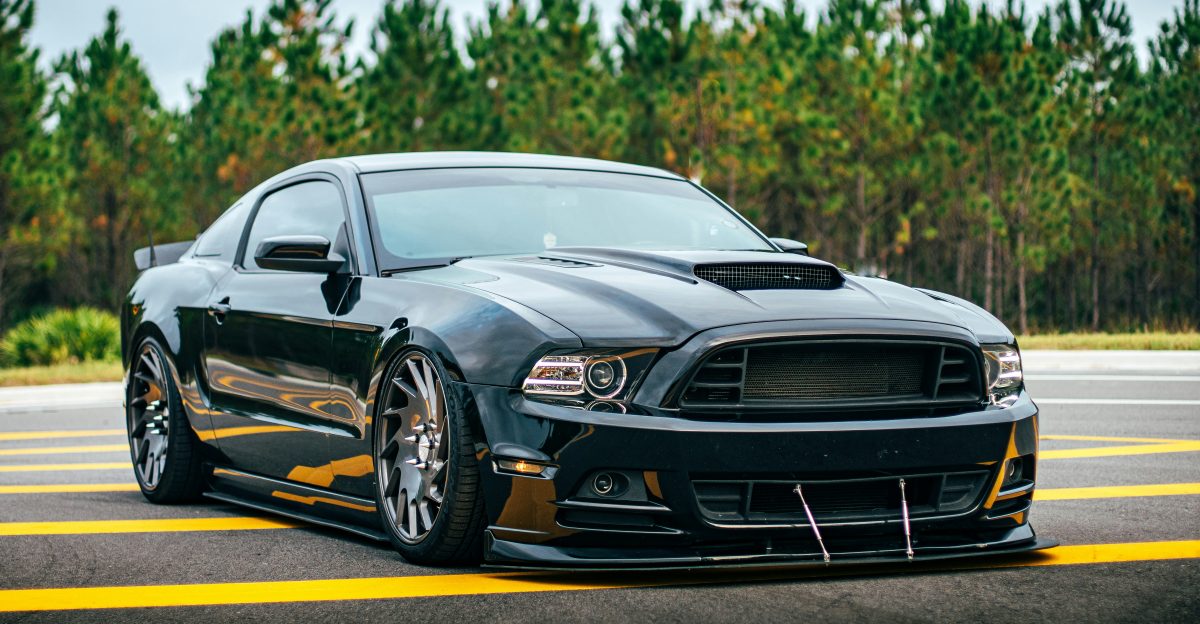 black coupe on road surrounded with trees
