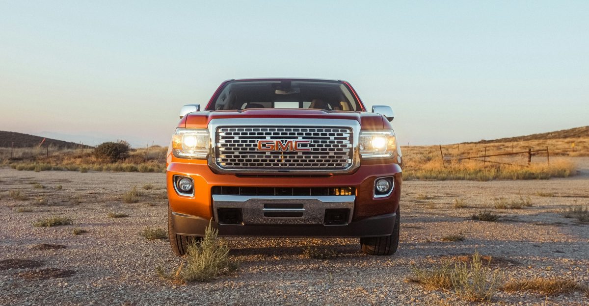 red Isuzu pickup truck under a calm blue sky