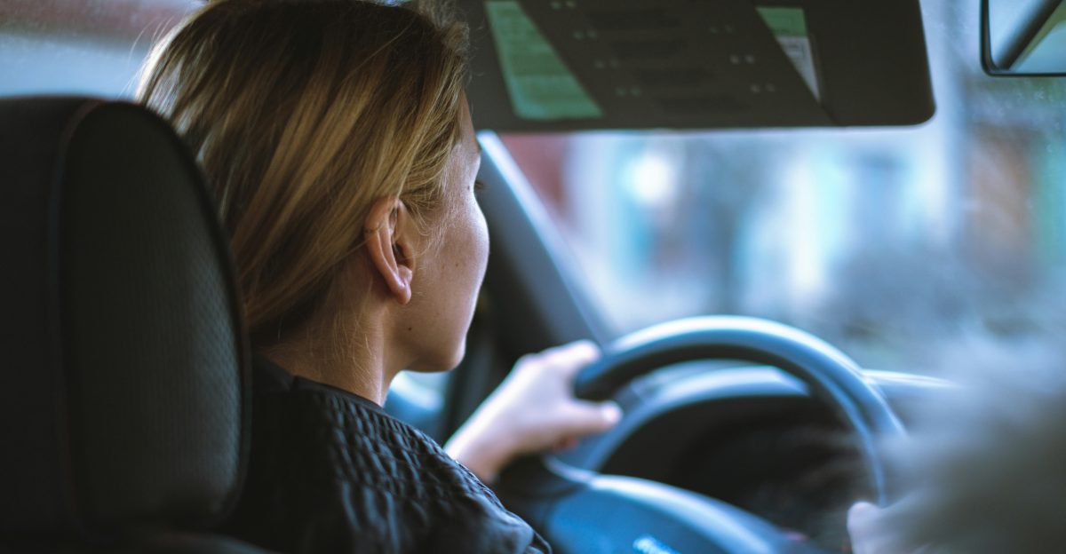 a woman sitting in a car with a steering wheel