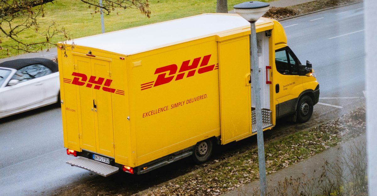 white and orange box truck parked near bare trees during daytime