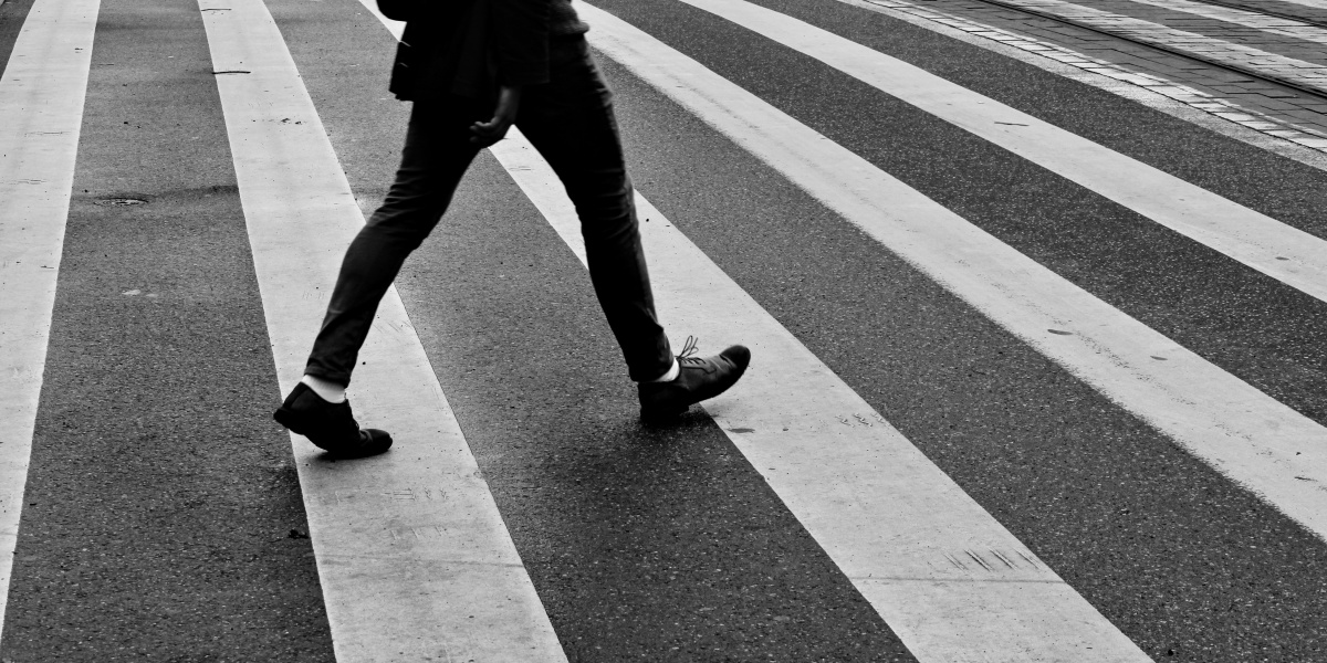 person in black pants and black sneakers walking on pedestrian lane