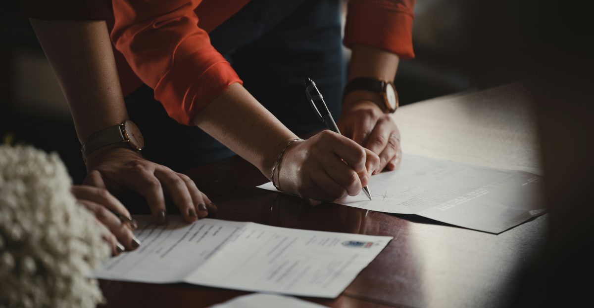 person in orange long sleeve shirt writing on white paper