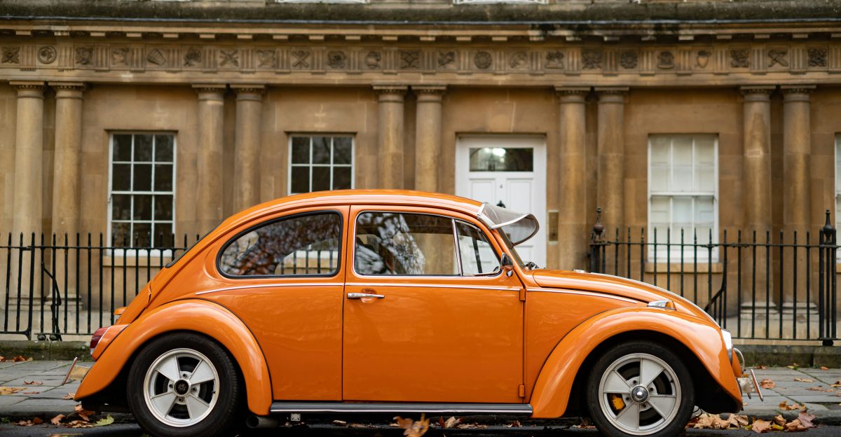 orange volkswagen beetle parked near building