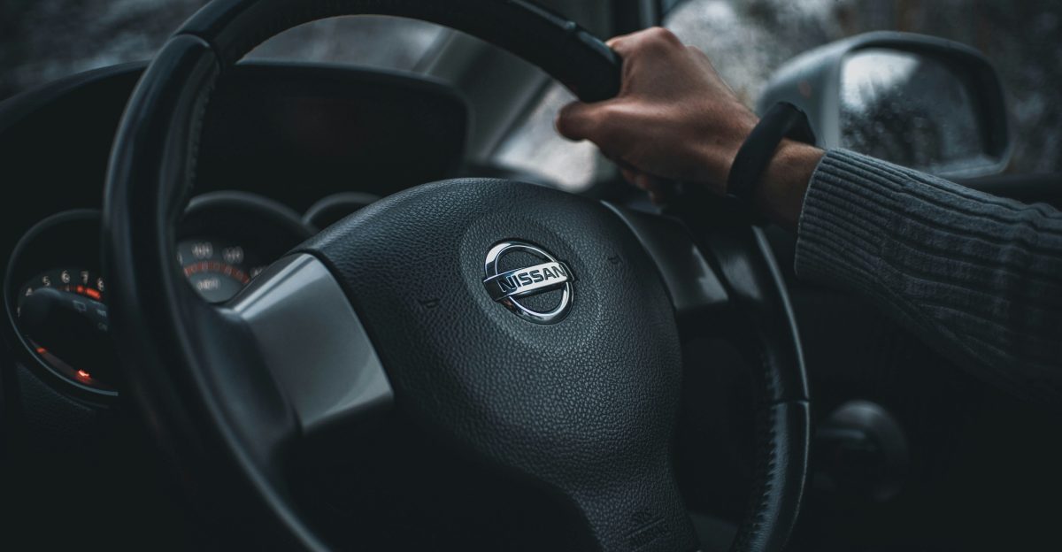person holding black nissan steering wheel