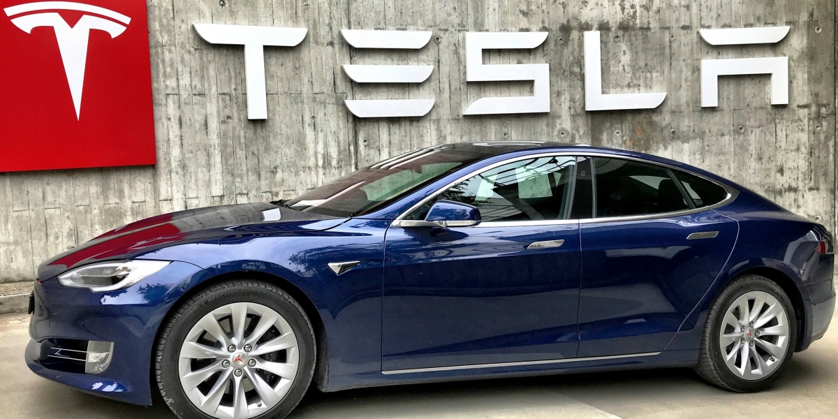 blue coupe parked beside white wall