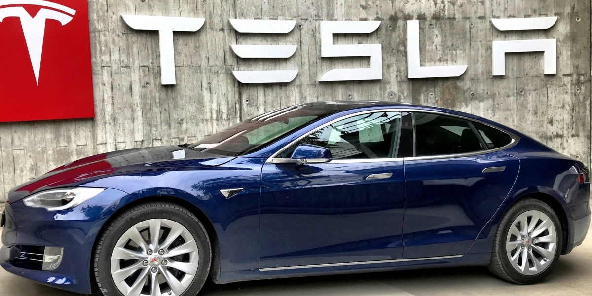 blue coupe parked beside white wall