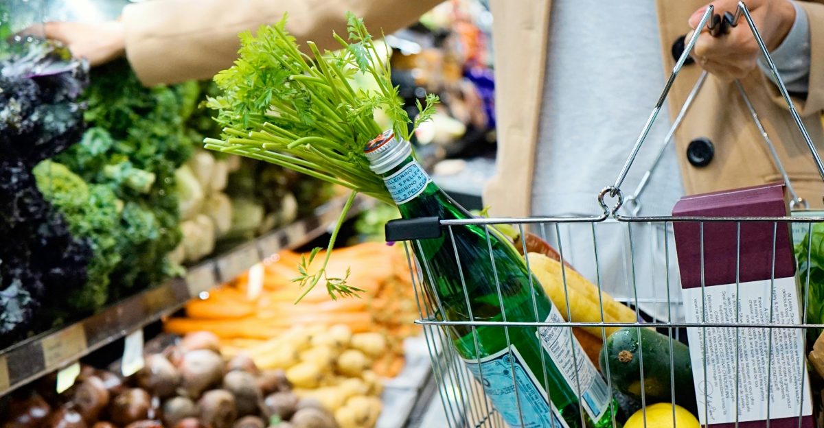 woman in white coat holding green shopping cart