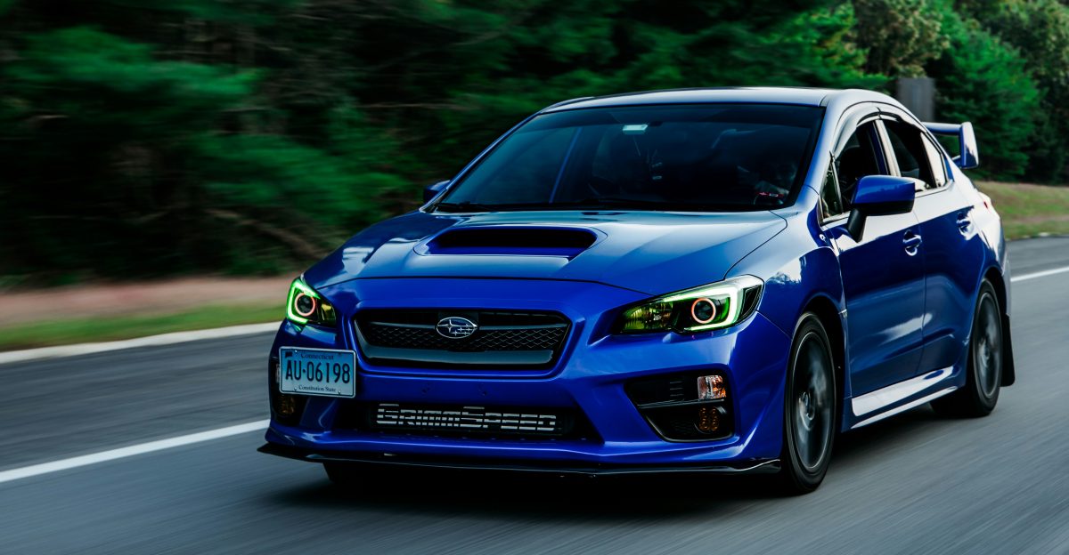 a blue subarunt is driving down the road
