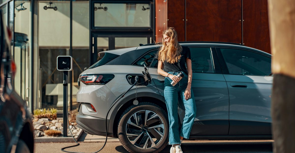 a woman standing next to a blue car