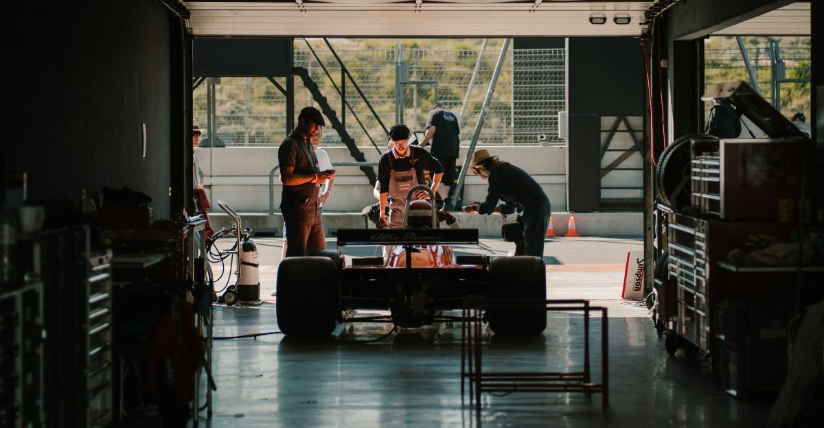 a group of people standing around a car in a garage