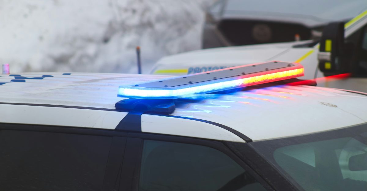 a police car with its lights on in the snow