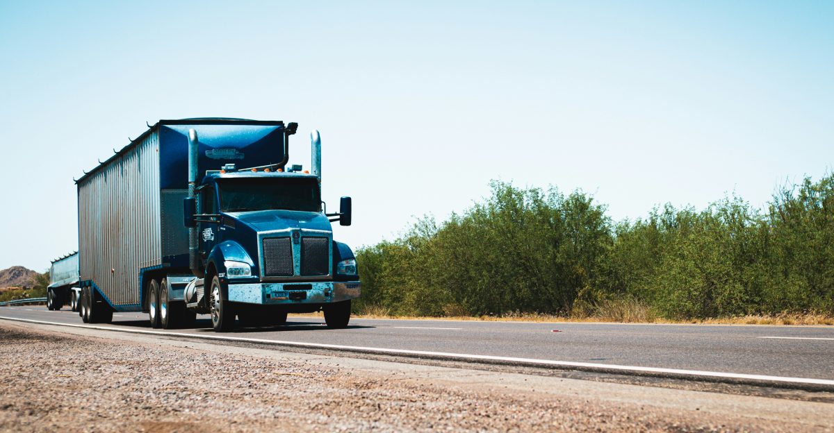 A semi truck driving down the road in the desert