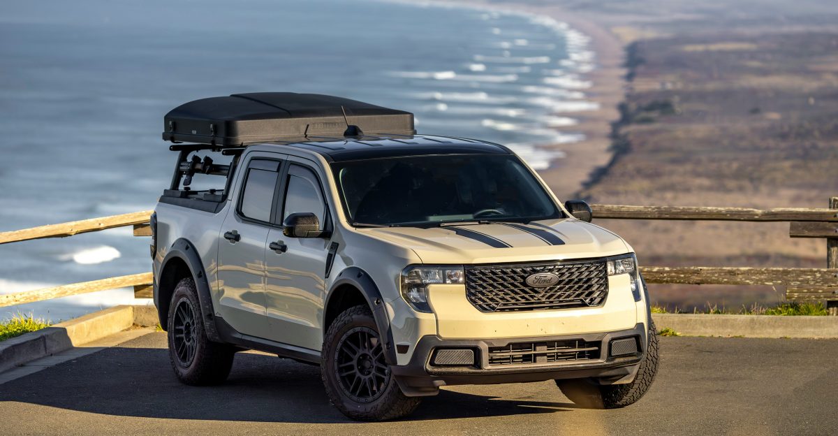 Tan pickup truck with rooftop tent parked overlooking ocean