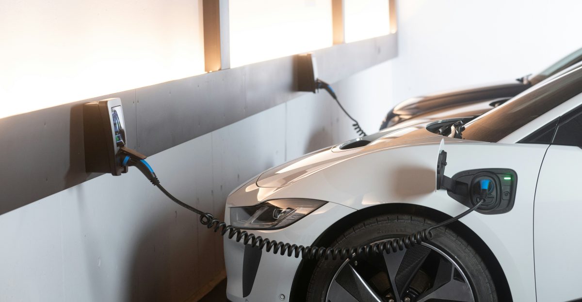 White electric car charging at a station