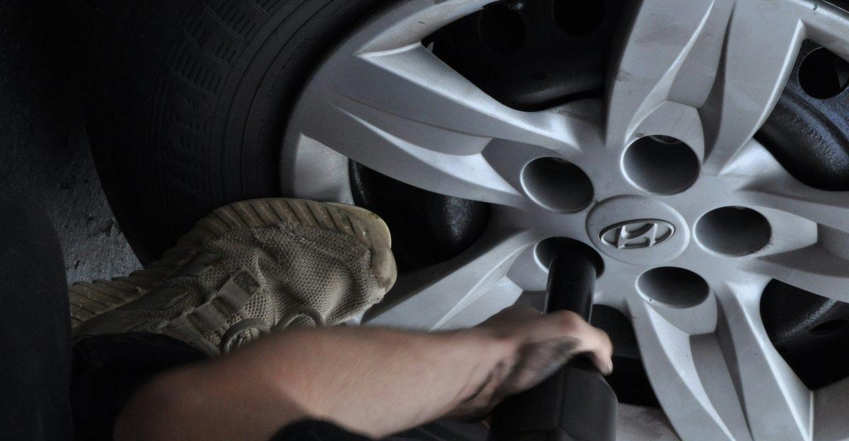 Mechanic using impact wrench on car wheel