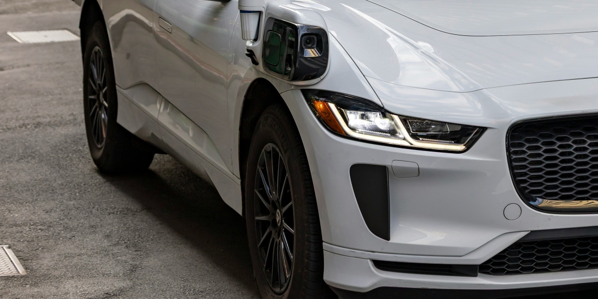 A white self-driving car on a city street.