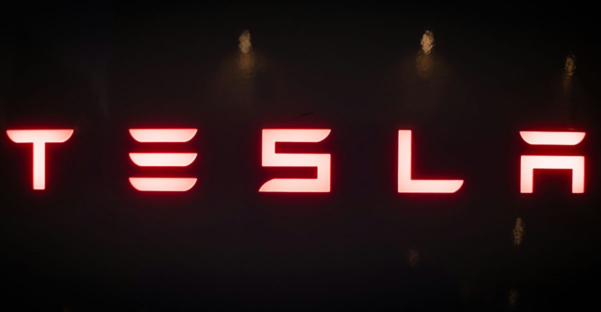 Red tesla logo on a dark background