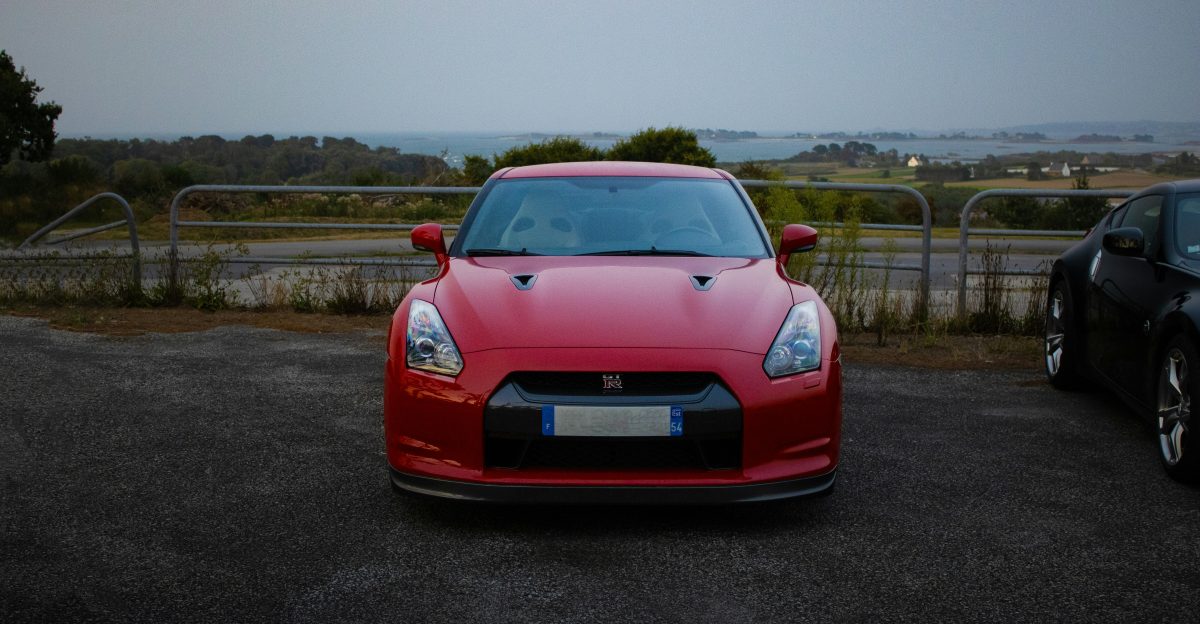 Red sports car parked outdoors with ocean view