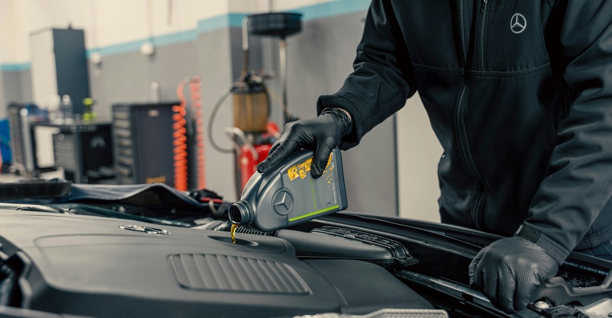 Mechanic pouring oil into car engine