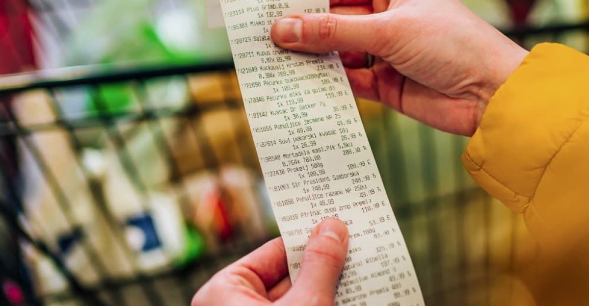 Woman checking the bill when paying at a supermarket by Susan Healey