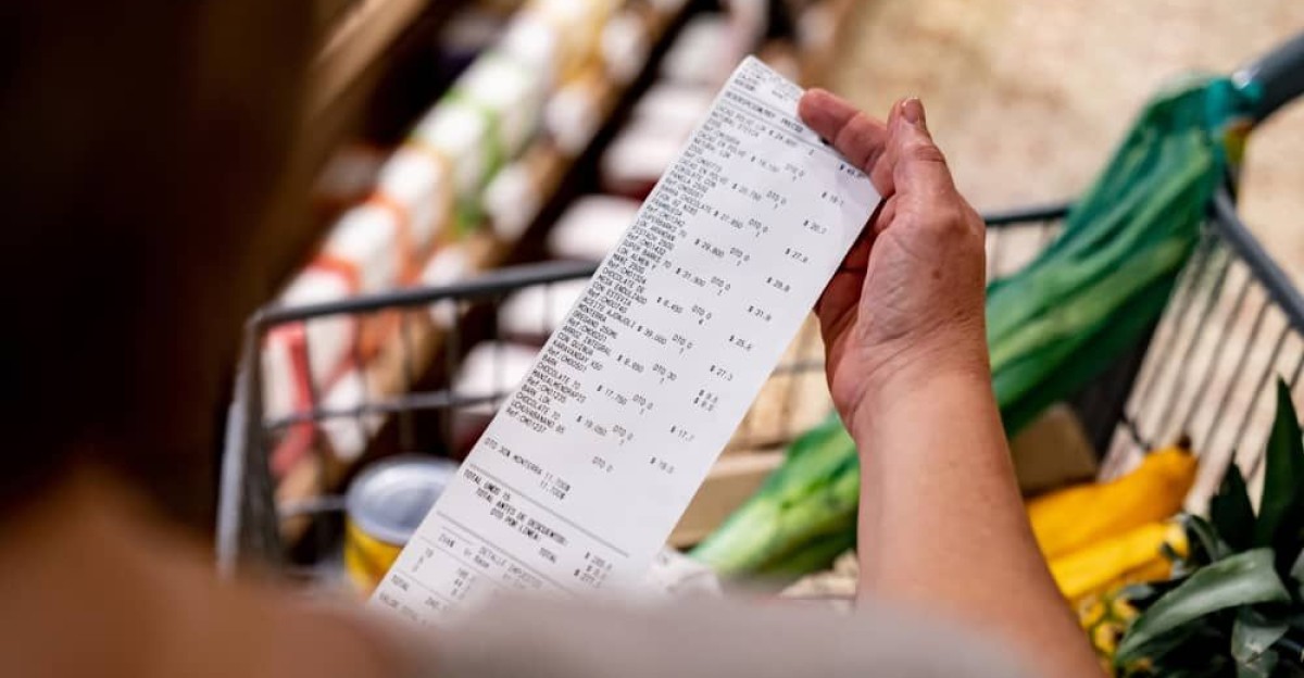 Woman looking at a receipt after shopping at the supermarket by carolyn cole