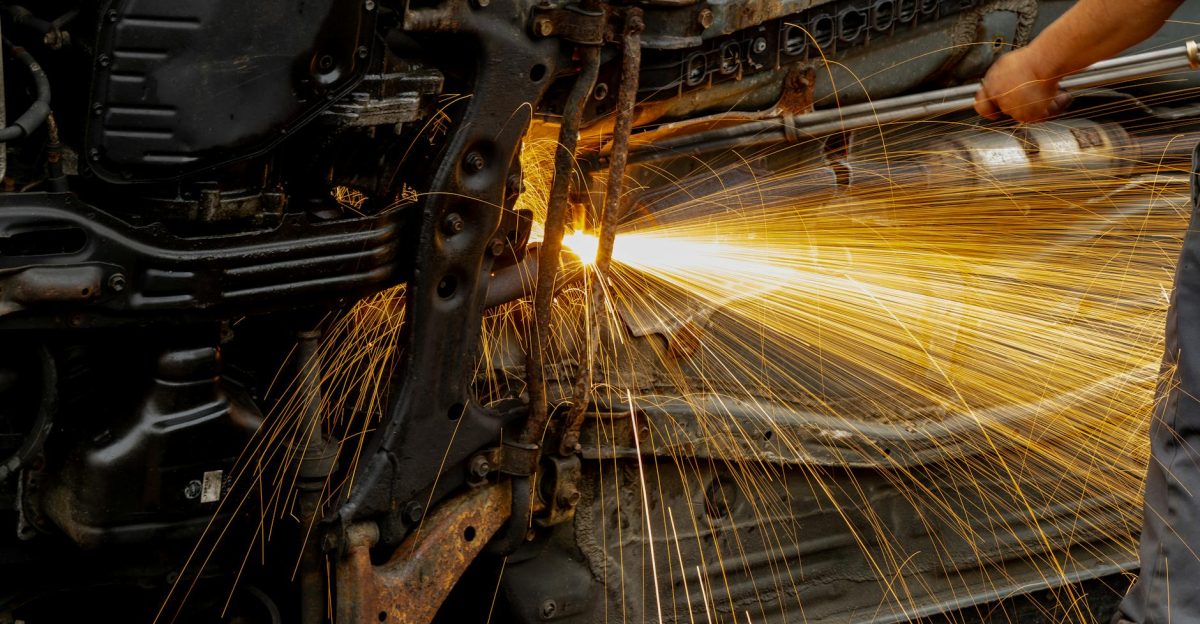 Mechanic welding car engine parts with bright sparks flying Hands-on automotive repair scene in workshop