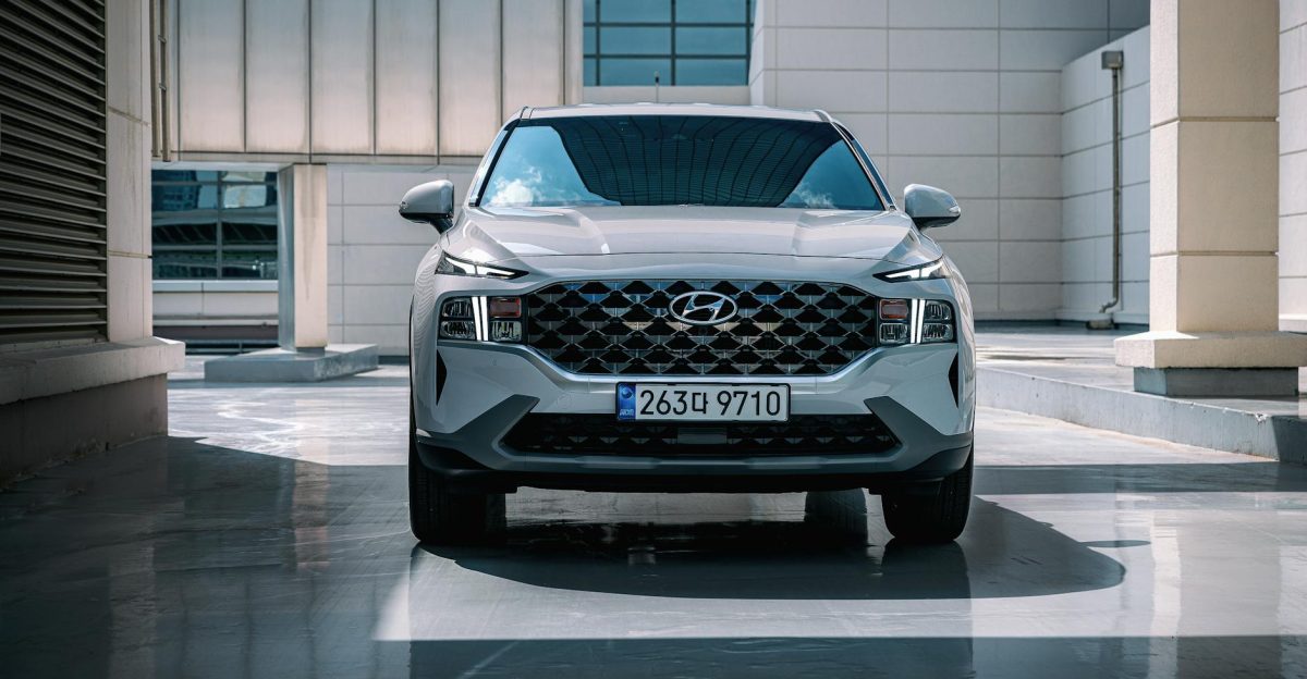 Front view of a white Hyundai Santa Fe SUV parked in an urban setting with sleek architecture