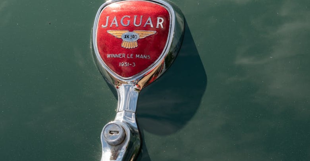 Close-up of a classic Jaguar car emblem on a vintage green vehicle