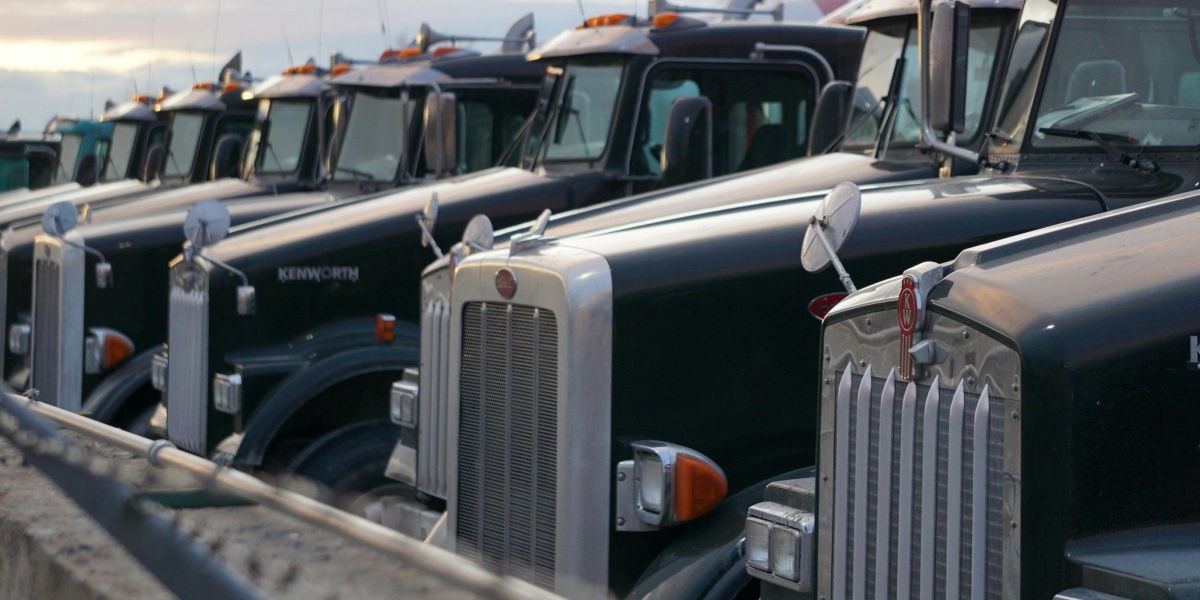 Classic Kenworth trucks lined up outdoors, showcasing heavy-duty retro design.