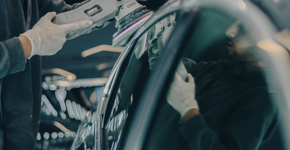 Close-up of car detailing process with polishing machine and reflective surface in workshop