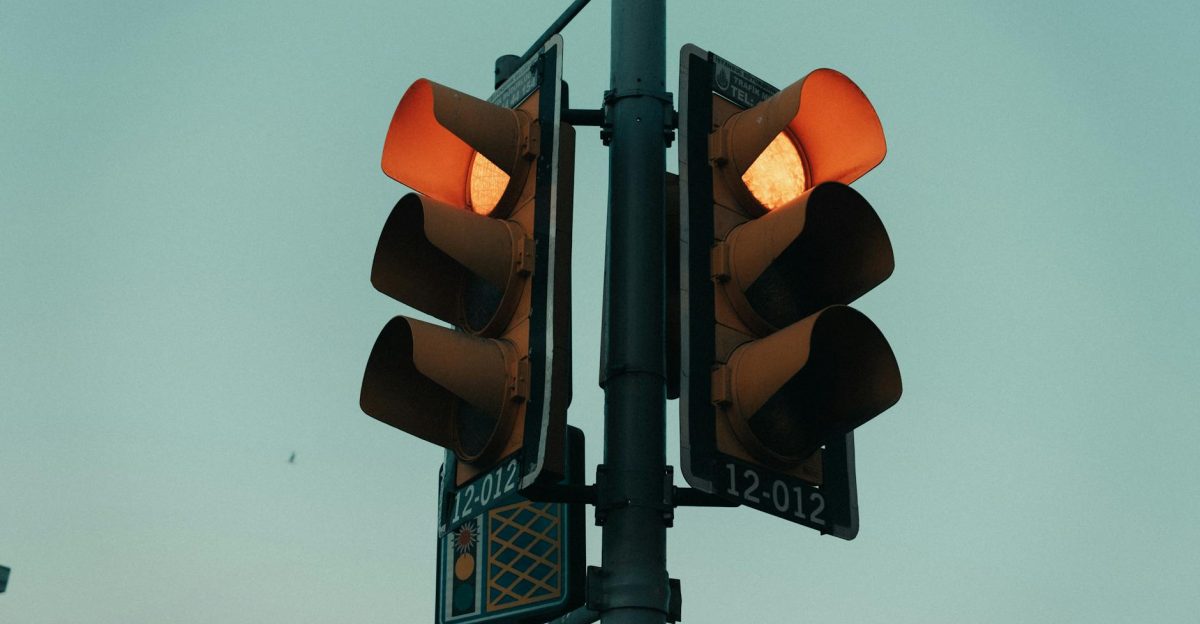 A close-up view of a traffic light glowing in an urban setting under the evening sky
